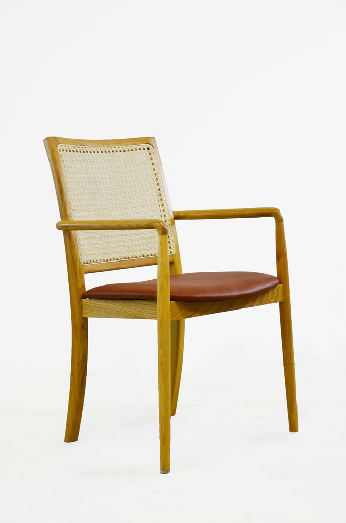The armchair gives a comfortable seat with a leather cushion, woven natural cane, and wooden frame. 